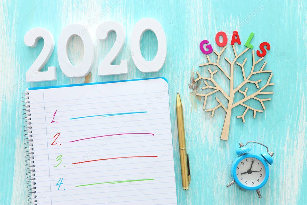 Business concept of top view 2020 goals list with notebook over blue wooden desk