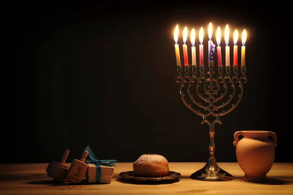 Релігійне зображення єврейського свята Ханука на фоні мелахи (традиційні канделябри), прядіння зверху та пончика — стокове фото