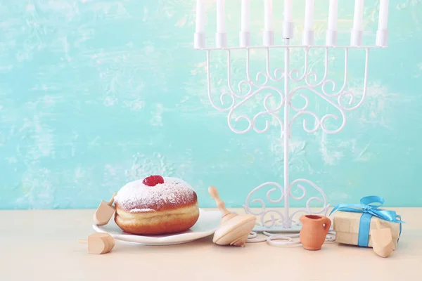 Imagen religiosa de vacaciones judías fondo Hanukkah con menorah (candelabros tradicionales), peonza y rosquilla sobre fondo azul pastel —  Fotos de Stock