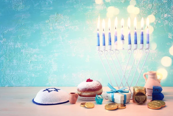 Religie beeld van joodse vakantie Chanoeka achtergrond met menorah (traditionele kandelaar), spinnen top en donut over pastel blauwe achtergrond — Stockfoto