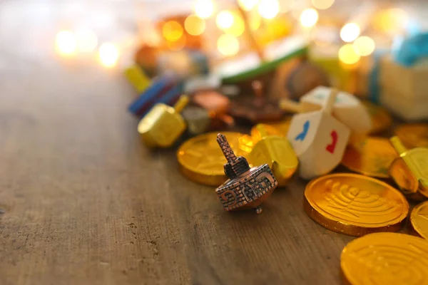 Náboženský koncept židovské dovolené Chanuka s dřevěnými dreidely (točící se vršek) a čokoládovými mincemi na dřevěném stole — Stock fotografie