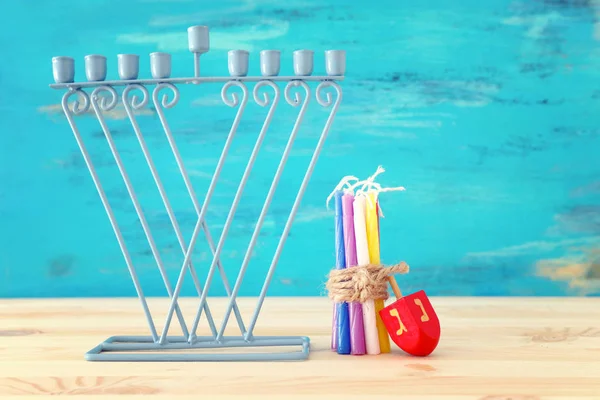 Imagen religiosa de fiesta judía Hanukkah con menorah (candelabro tradicional) y la tapa giratoria sobre la mesa de madera y el fondo azul —  Fotos de Stock