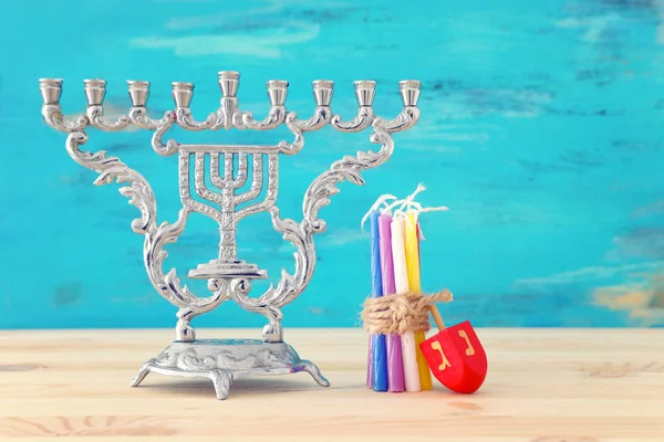 Imagen religiosa de fiesta judía Hanukkah con menorah (candelabro tradicional) y la tapa giratoria sobre la mesa de madera y el fondo azul —  Fotos de Stock