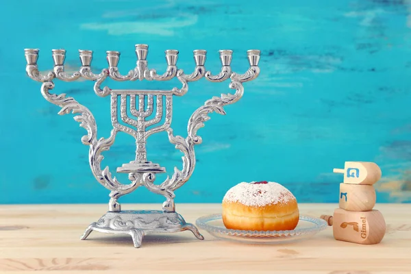 Imagen religiosa de fiesta judía Hanukkah con menorah (candelabro tradicional), peonza y rosquilla sobre mesa de madera y fondo azul — Foto de Stock