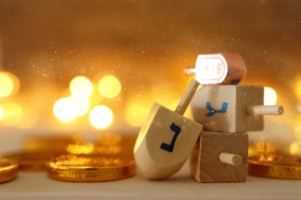 Concepto religioso de vacaciones judías Hanukkah con dreidels de madera (spinning top) y monedas de chocolate sobre mesa de madera y fondo de luces bokeh — Foto de Stock