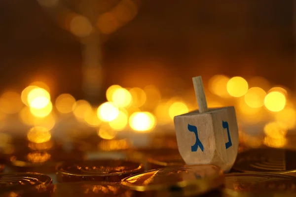 Religion concept of of jewish holiday Hanukkah with wooden dreidels (spinning top) and chocolate coins over wooden table and bokeh lights background — Stock Photo, Image