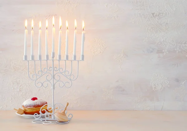 Религиозный образ еврейского праздника Ханука фон с менорой (традиционные канделябры), спиннинг сверху и пончик на белом фоне — стоковое фото