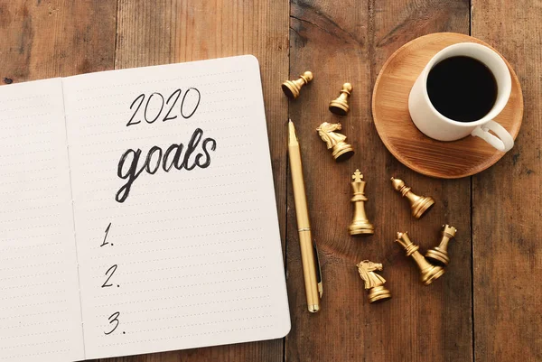 Business concept of top view 2020 goals list with notebook, chess figures over wooden desk — Stock Photo, Image