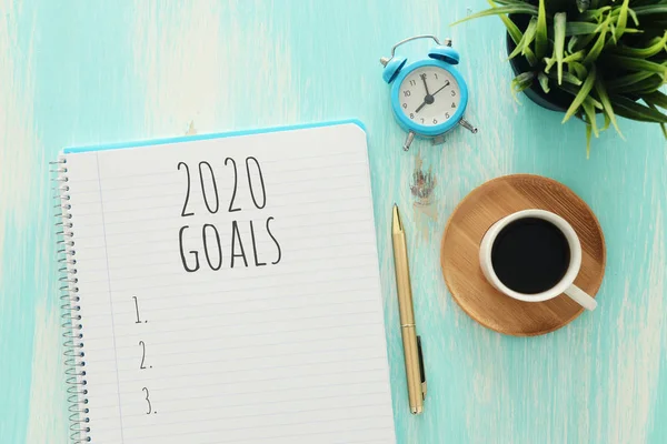 Zakelijk concept van top view 2020 doelen lijst met notebook, kopje koffie over blauw houten bureau — Stockfoto