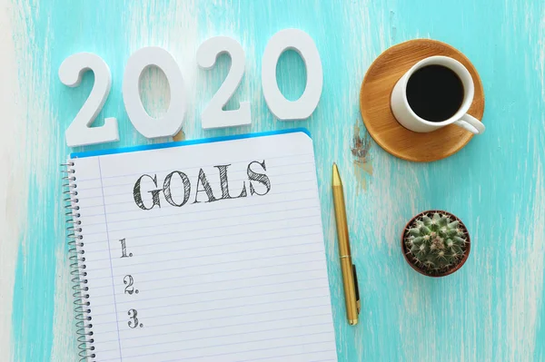 Obchodní koncept top view 2020 seznam cílů s notebookem, šálek kávy přes modrý dřevěný stůl — Stock fotografie