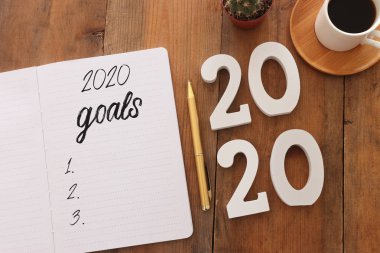 Üst görünüm iş konsepti 2020 gol listesi, not defteri, ahşap masa üzerinde bir fincan kahve