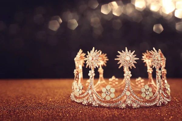 Låg nyckel bild av vacker drottning / kung krona över guld glitter bord. Årgångsfiltrerad. fantasi medeltid — Stockfoto