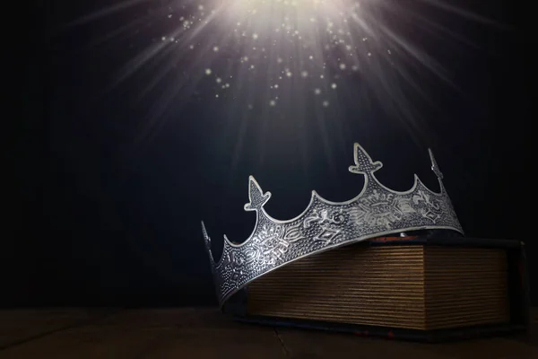 Imagen de llave baja de hermosa corona reina / rey sobre libro viejo y mesa de madera. filtrado vintage. fantasía período medieval — Foto de Stock