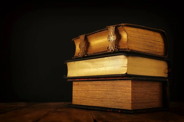 Halom antik könyvek a régi fából készült asztal. Fantasy középkori időszak és a vallási koncepció. — Stock Fotó