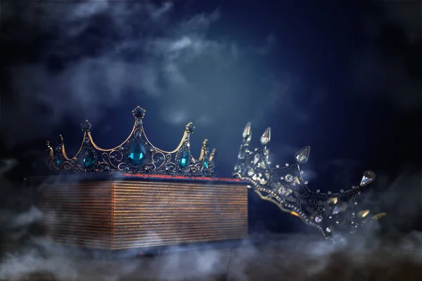 Nízký klíčový obraz krásné královny / krále koruny přes starou knihu a dřevěný stůl. ročník filtrován. fantasy středověké období. mlha a mlha — Stock fotografie