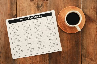 Üst görünüm iş konsepti. Not defterli 2020 plan listesi. Mavi ahşap masa üzerinde bir fincan kahve.