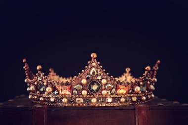 Tahta masanın üzerindeki güzel kraliçe ve kral tacının gösterişsiz görüntüsü. Eski model filtrelenmiş. fantezi ortaçağ dönemi
