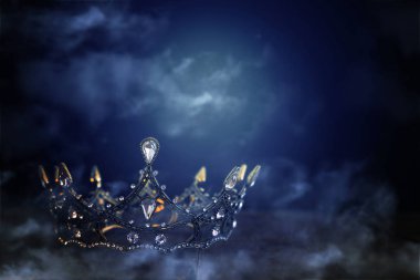 Tahta masanın üzerindeki güzel kraliçe ve kral tacının gösterişsiz görüntüsü. Eski model filtrelenmiş. fantezi ortaçağ dönemi. sis ve sis