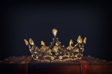 Tahta masanın üzerindeki güzel kraliçe ve kral tacının gösterişsiz görüntüsü. Eski model filtrelenmiş. fantezi ortaçağ dönemi