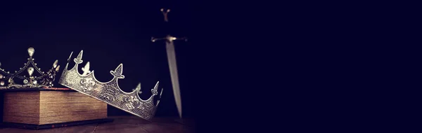 Niedrige Schlüsselbild der schönen Königin / König Krone über antiken Buch neben Schwert. Mittelalterliche Fantasie. Selektiver Fokus — Stockfoto