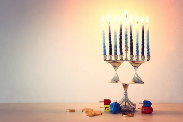 Religie beeld van joodse vakantie Chanoeka met menorah (traditionele kandelaar), spinnen top en donut over houten achtergrond — Stockfoto