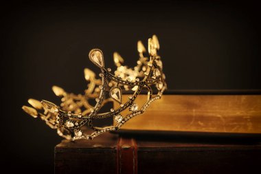 Eski kitap ve ahşap masa üzerinde güzel kraliçe / kral tacının gösterişsiz görüntüsü. Eski model filtrelenmiş. fantezi ortaçağ dönemi