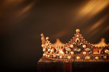 Tahta masanın üzerindeki güzel kraliçe ve kral tacının gösterişsiz görüntüsü. Eski model filtrelenmiş. fantezi ortaçağ dönemi