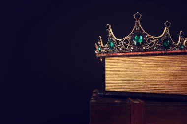 Eski kitap ve ahşap masa üzerinde güzel kraliçe / kral tacının gösterişsiz görüntüsü. Eski model filtrelenmiş. fantezi ortaçağ dönemi