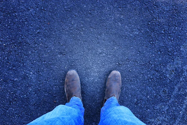 Top view photo of person in jeans and retro shoes standing over asphalt road — Stock Photo, Image