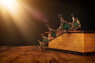 Eski kitap ve ahşap masa üzerinde güzel kraliçe / kral tacının gösterişsiz görüntüsü. Eski model filtrelenmiş. fantezi ortaçağ dönemi