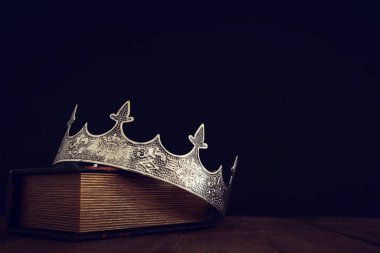 Eski kitap ve ahşap masa üzerinde güzel kraliçe / kral tacının gösterişsiz görüntüsü. Eski model filtrelenmiş. fantezi ortaçağ dönemi