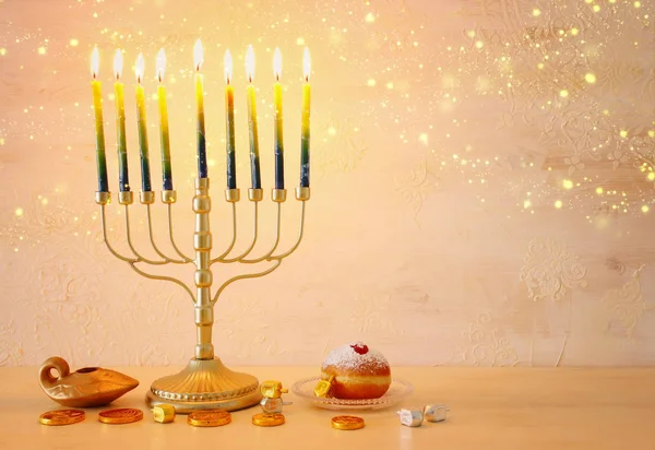 Религиозный образ еврейского праздника Ханука с менорой (традиционная канделябра), крутящийся верх и пончик на деревянном фоне — стоковое фото