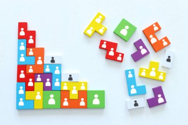 Ahşap masa, insan kaynakları ve yönetim kavramının üzerinde simgeler bulunan tangram bulmaca bloklarının iş konsepti