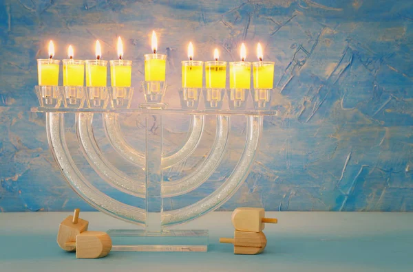 image of jewish holiday Hanukkah background with crystal menorah (traditional candelabra) and colorful oil candles