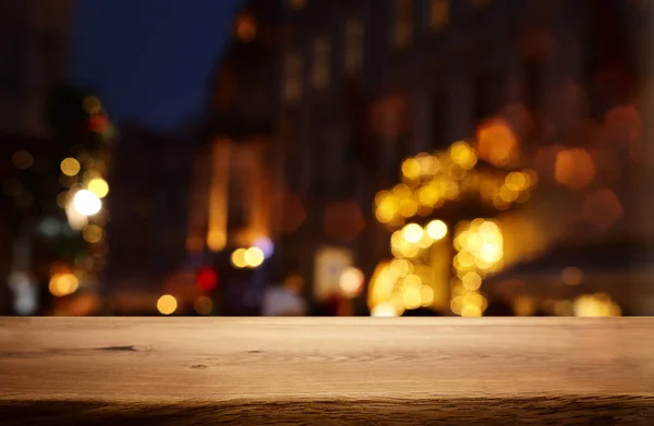 Φόντο εικόνα του ξύλινου τραπεζιού μπροστά από το δρόμο αφηρημένη θολή φώτα προβολή — Φωτογραφία Αρχείου