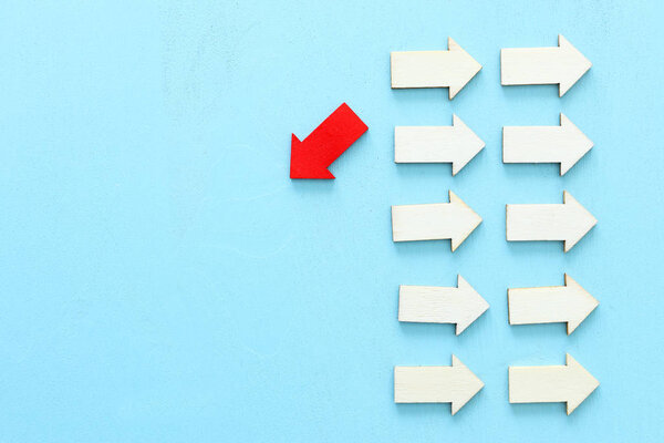 Концепция изображения красной стрелки, направленной в противоположном направлении от других стрелок в группе. Метафора индивидуальности и амбиций
