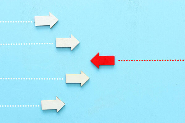 Concept image of red arrow facing opposite direction from other arrows in group. Individuality and ambition metaphor