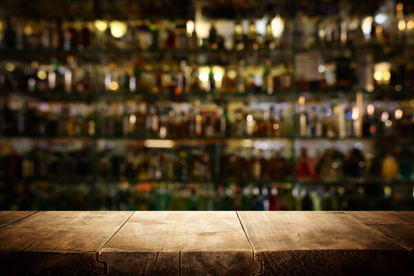 Изображение деревянного стола перед размытыми огнями ресторана