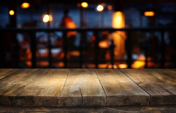 ภาพพื้นหลังของตารางไม้ด้านหน้าของไฟร้านอาหารที่ไม่ชัดเจน — ภาพถ่ายสต็อก