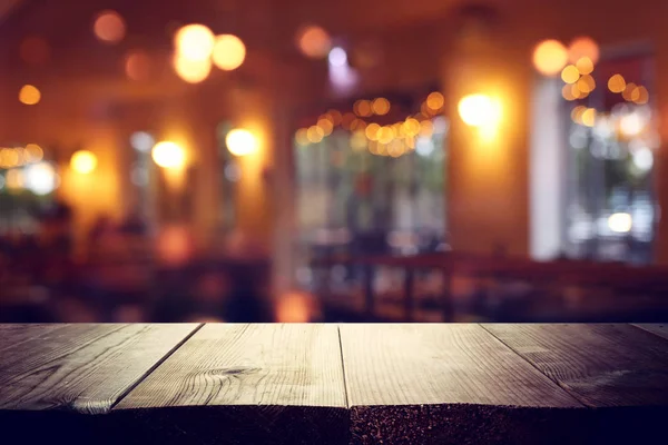 Background Image of wooden table in front of abstract blurred restaurant lights — Stock Photo, Image