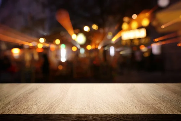 Background Image of wooden table in front of abstract blurred restaurant lights — Stock Photo, Image
