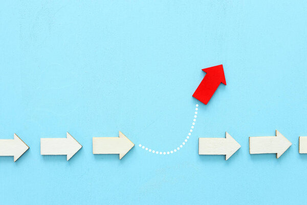 Концепция изображения красной стрелки, направленной в противоположном направлении от других стрелок в группе. Метафора индивидуальности и амбиций
