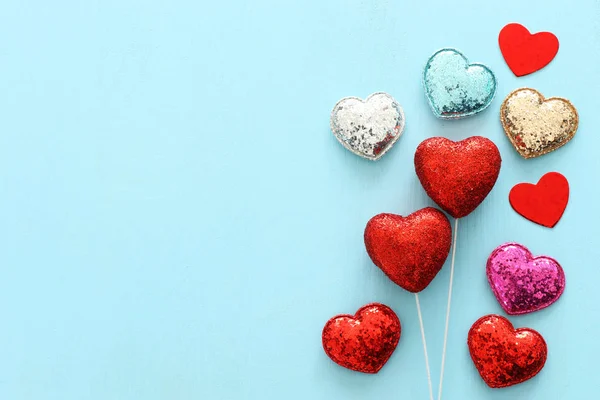 Concetto di San Valentino. cuori brillantini rossi su sfondo blu di legno. Composizione laica piatta — Foto Stock