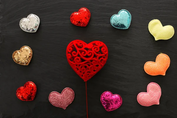 Concepto de San Valentín. corazones de purpurina roja sobre fondo negro. Composición laica plana — Foto de Stock