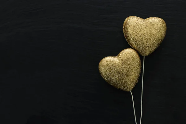 Valentinstag-Konzept. Gold glitzernde Herzen auf schwarzem Hintergrund. flache Verlegekomposition — Stockfoto