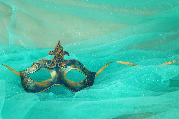 Foto de ouro elegante e delicado e máscara veneziana azul sobre fundo chiffon hortelã — Fotografia de Stock