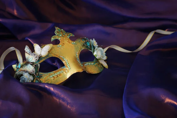 Photo of elegant and delicate gold Venetian mask over purple silk background — 스톡 사진