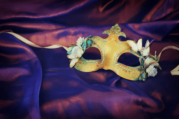 Photo d'un élégant et délicat masque vénitien doré sur fond de soie violette — Photo