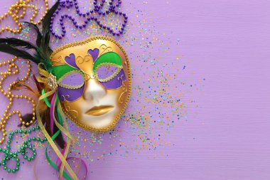 Mardi Gras maskesi, Venedik maskesi ve mor arka planda boncuklar. Yukarıdan görünüm