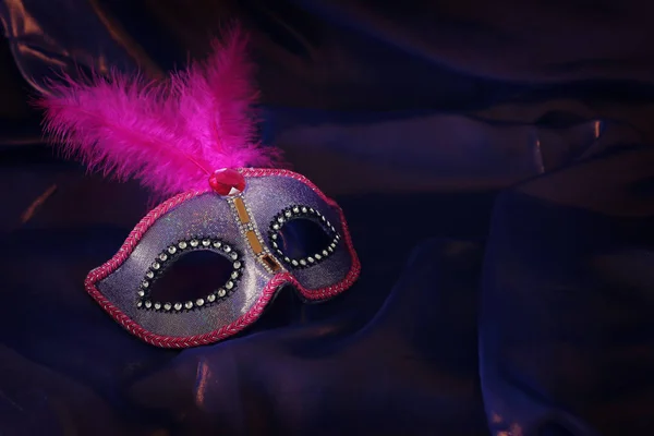 Фото элегантной и нежной розовой венецианской маски на фиолетовом шелковом фоне — стоковое фото